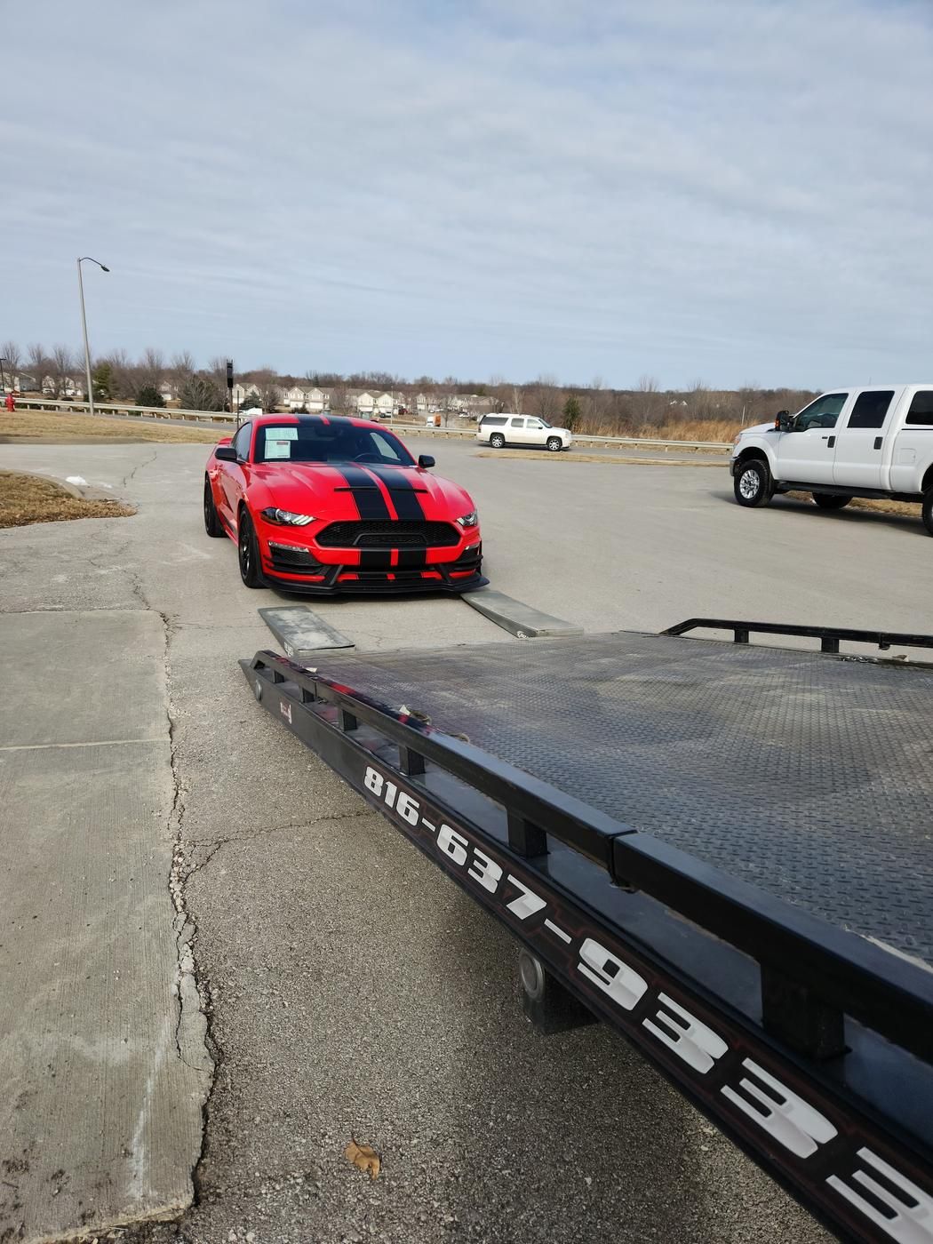 Red Shelby Mustang lining up to the flatbed ramps